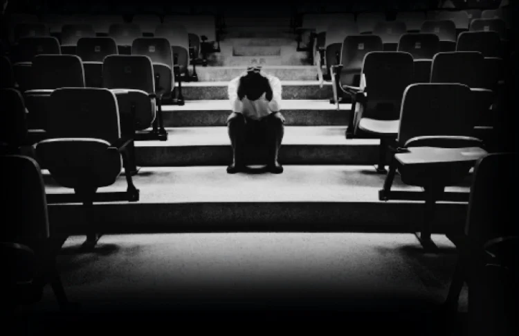 A coach sitting alone in an empty auditorium
